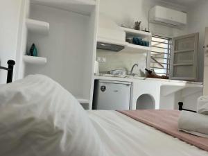 uma cozinha branca com uma cama e um lavatório em AmatoNostro em Mandrakia