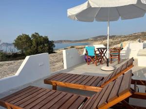 eine Terrasse mit einem Tisch, einem Sonnenschirm und Stühlen in der Unterkunft AmatoNostro in Mandrakia