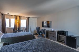 a hotel room with two beds and a flat screen tv at Le 2020 Charlevoix in La Malbaie