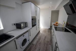 a kitchen with white cabinets and a washer and dryer at Abingdon House Workstays UK in Middlesbrough