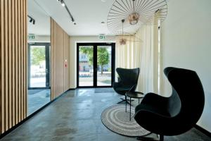 un vestíbulo con 2 sillas negras y una alfombra en BlueApart Apartamenty Portowa, en Jastarnia