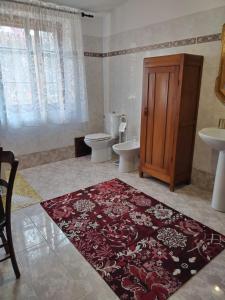 y baño con aseo, lavamanos y alfombra. en Il Casale Del Cortonese, en Sassari