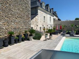 une terrasse avec une piscine en face d'un bâtiment dans l'établissement La Douce France Trianon, à Chinon