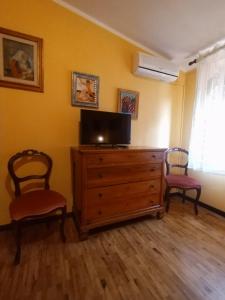 sala de estar con TV en un tocador y 2 sillas en Il Casale Del Cortonese, en Sassari