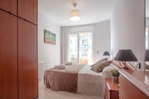a white bedroom with a bed and a window at Fantástico apartamento en la playa. A/A y vistas in Pineda de Mar