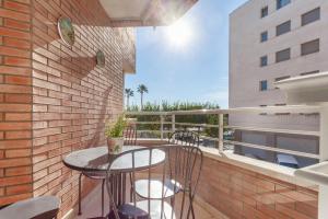 a balcony with a table and chairs on a brick wall at Fantástico apartamento en la playa. A/A y vistas in Pineda de Mar