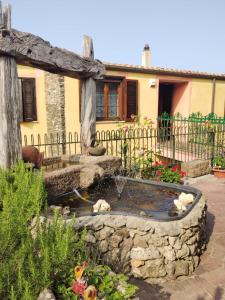 un jardín con una fuente de piedra frente a una casa en Il Casale Del Cortonese, en Sassari