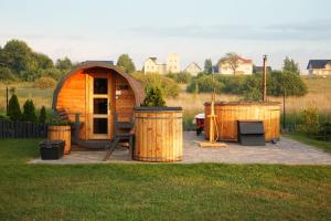 a wooden cabin with two barrels in the grass at Resort Mielenko in Mielenko