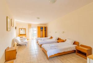 a hotel room with three beds and two chairs at Thalassa Apartments in Kallithea Halkidikis