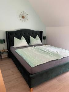 ein Bett mit einem schwarzen Kopfteil in einem Schlafzimmer in der Unterkunft Ferienwohnung Unter den Linden in Halbe