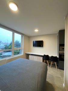Cet appartement comprend une chambre avec un lit et deux chaises ainsi qu'une cuisine. dans l'établissement Epicentro Suites Apart Hotel - Valdivia, à Valdivia