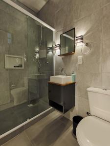 uma casa de banho com um chuveiro, um lavatório e um WC. em VILLA BILAC 04 - Amplo Studio próxima à Vila Germânica em Blumenau