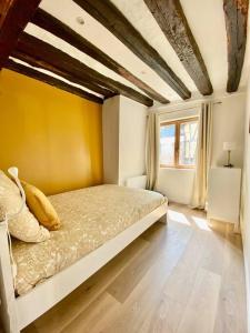 1 dormitorio con 1 cama con pared amarilla y ventana en Le Mimosa, en Rouen