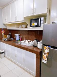 uma cozinha com armários brancos, um lavatório e um micro-ondas em The Doll House 1 em Orani