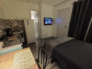 a room with a bed and a kitchen with a television at VILLA BILAC - Studios próximo à Vila Germânica Bairro da Velha in Blumenau +35 photos