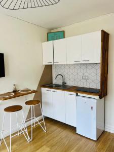 a kitchen with white cabinets and a sink and two stools at Biarritz, hyper centre, 50M plages, wifi in Biarritz