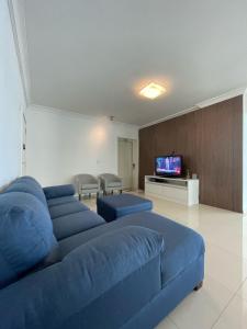 a living room with a blue couch and a tv at Linda Vista, Um apartamento por andar, 3 Suítes, 2 Garagens in Balneário Camboriú