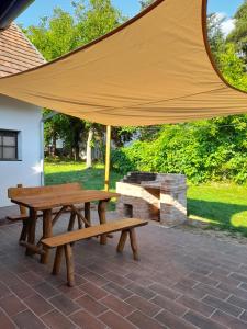 een picknicktafel en een grote parasol op een patio bij Börzsöny Aranya Vendégház in Nagybörzsöny