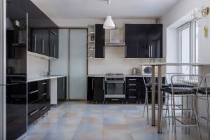 una cocina con armarios negros, mesa y sillas en Naukova Street Appartamento, en Leópolis