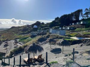 a beach with straw umbrellas and chairs on the sand at Recondito Lodge in Pichilemu