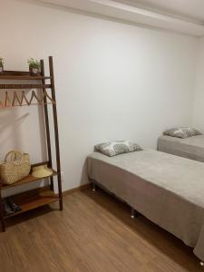 舊巴拉的住宿－Apartamento pé na areia，一间卧室设有两张床、书架和白色的墙壁。