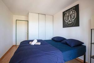 een slaapkamer met een bed met blauwe lakens en blauwe kussens bij *Appt Rue Tour Gayraud, 4 Pers, Parking, Wi-Fi* in Montpellier