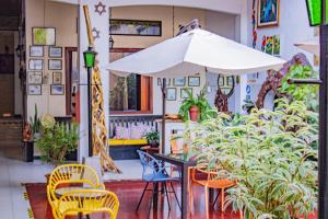 um pátio com uma mesa, cadeiras e um guarda-sol em Hotel La Casona Iquitos em Iquitos