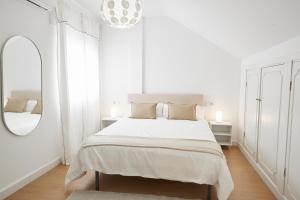 a white bedroom with a large bed and a mirror at City Center Penthouse with Solarium 2 minutes from the Beach in Fuengirola