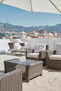 a patio with wicker chairs and tables on a roof at City Center Penthouse with Solarium 2 minutes from the Beach in Fuengirola