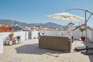 a patio with an umbrella and chairs and buildings at City Center Penthouse with Solarium 2 minutes from the Beach in Fuengirola