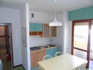 リニャーノ・サッビアドーロにあるCondominio Ginestraの青いキャビネットとテーブル付きのキッチンが備わります。