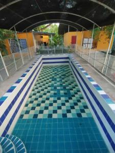 a swimming pool with blue and white tiles on the floor at Finca turisrica bioaldea eywa todo un oasis in Neiva