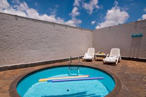 a swimming pool with two chairs and a table at STATUS Motel in Belo Horizonte