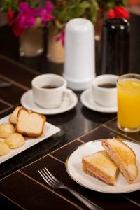 a table with plates of toast and coffee and orange juice at STATUS Motel in Belo Horizonte