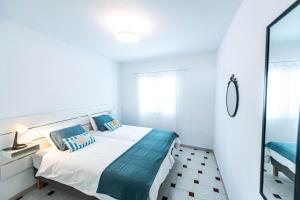 ein weißes Schlafzimmer mit einem Bett und einem Spiegel in der Unterkunft Nublo in Las Playitas