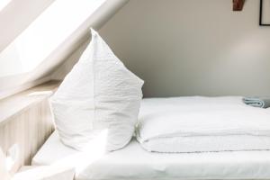 a white bed with a pillow on top of it at Heberer Hof in Schneverdingen