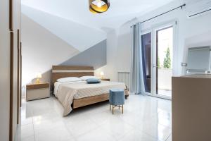 a white bedroom with a bed and a blue chair at Casa vacanza lido in Sciacca