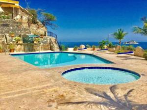 a swimming pool in front of a house with the ocean at Apartamento Rodadero frente a la playa in Rodadero