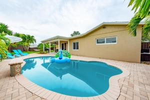 a swimming pool in front of a house at Colorful Home - Pool - Game Room - Basketball Court - BBQ & More in Fort Lauderdale +30 photos