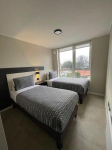 two beds in a room with two windows at Epicentro Suites Apart Hotel - Valdivia in Valdivia