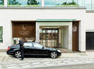 un hombre de pie junto a un coche negro delante de un edificio en COMO Metropolitan London, en Londres