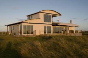 ein Haus auf einem Grasfeld in der Unterkunft Wytonia Beachfront Accommodation in Port Fairy