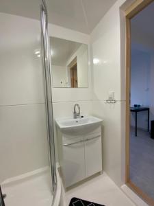 a white bathroom with a sink and a shower at Pokoje Victoria in Ustka
