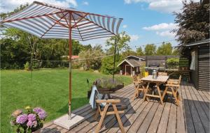 a wooden deck with an umbrella and a table and chairs at Nice Home In Jgerspris With Kitchen in Jægerspris