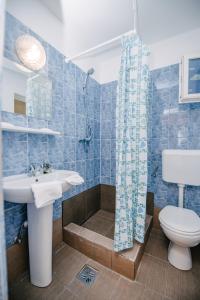 bagno piastrellato blu con lavandino e servizi igienici di Silver Villa a Băile Tuşnad