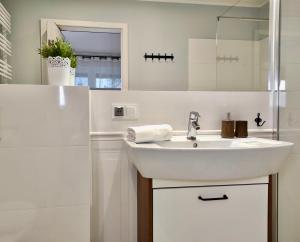 a white bathroom with a sink and a mirror at Apartamenty Turystyczne WillkasSen in Giżycko +38 photos
