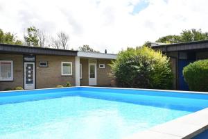 a large blue swimming pool in front of a house at Vrijvakantiehuis Houtenburgseweg 22 in Zoutelande