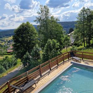 a swimming pool with two benches on a wooden deck at ATPeak Lodge Maison de Montagne d'exception in Xonrupt-Longemer