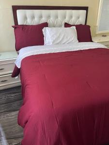 Cama grande de color rojo con sábanas y almohadas de color rojo y blanco en Digna alojamientos, en Juan Pedro