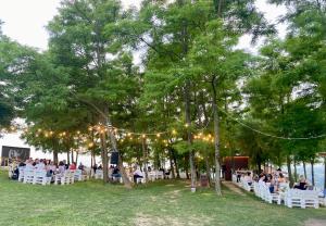 un groupe de personnes assises sous des chaises sous des arbres et des lumières dans l'établissement Kuća za odmor MUŠKAT, à Štrigova